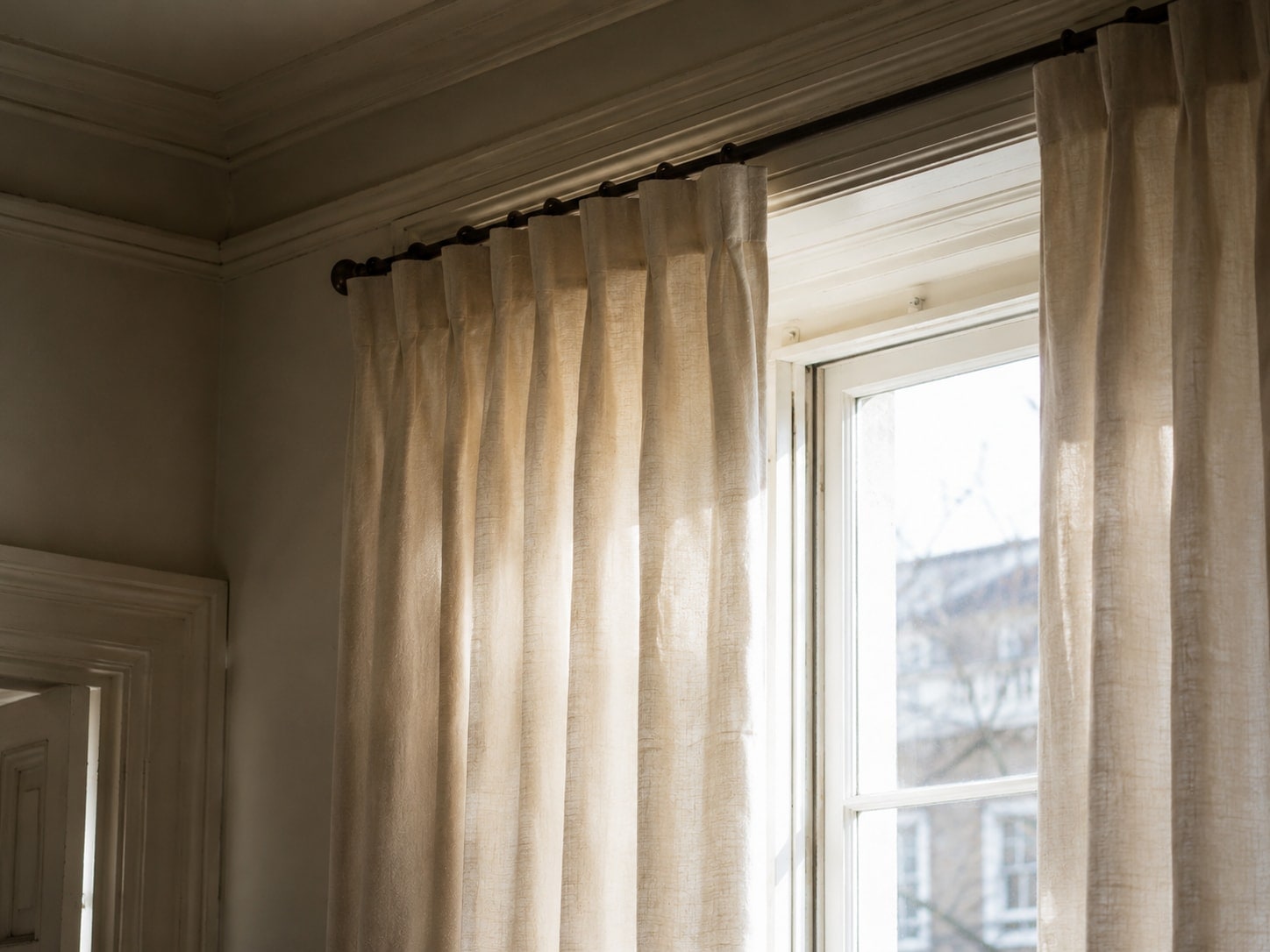 Linen curtains in pinch-pleat against window